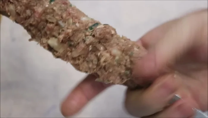 Using your whole hand, push down firmly on the meat to compact it onto the skewer.