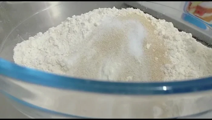 Combine flour, sugar, yeast, salt, baking powder, coconut milk powder, and ghee in a bowl.