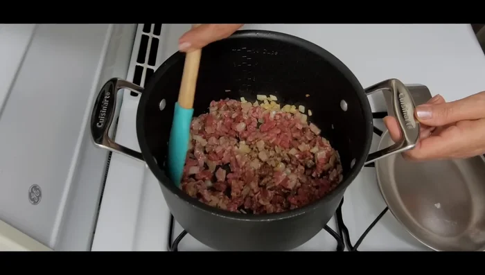 Stir the meat and onions with the spices until the meat is slightly cooked, then add water and cover. Allow to simmer until cooked (at least 1 hour).