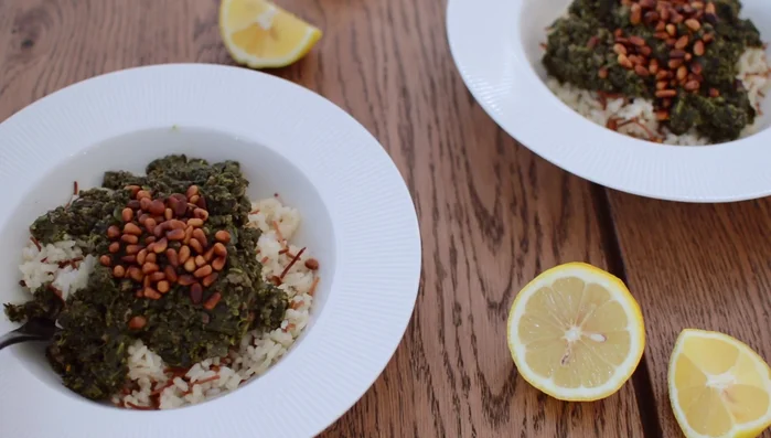 Layer rice, spinach, and remaining pine nuts in a serving dish. Garnish with lemon wedges.