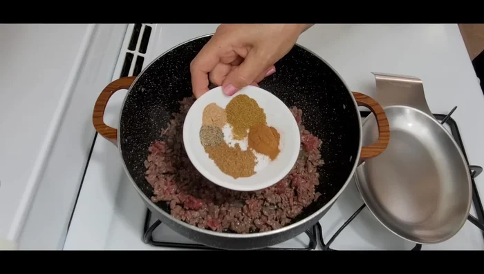Add cumin, cinnamon, seven spices, black pepper, and nutmeg to the meat. Stir.