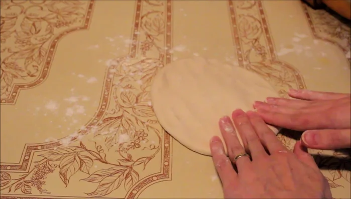 Take one dough ball, roll or stretch it into a large, thin, even sheet.