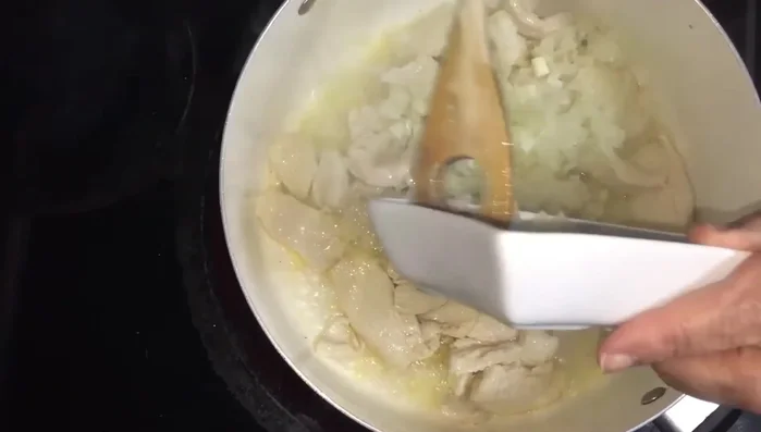 Add the sliced onions to the chicken and sauté until slightly translucent.