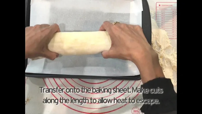 Transfer the pastry roll to a baking sheet and make slits along its length.