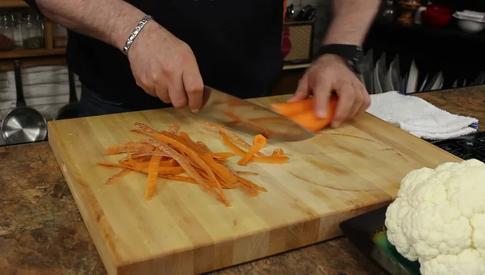 Peel carrots, chop both ends, and slice them in half. Then, slice them into quarter-inch thick pieces on an angle.