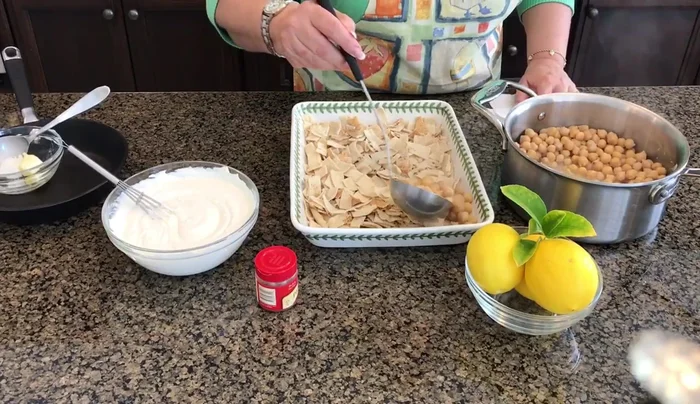 Assemble the dish: Layer the pita bread in a dish, followed by the warm garbanzo beans with their liquid, and finally top with the yogurt mixture.