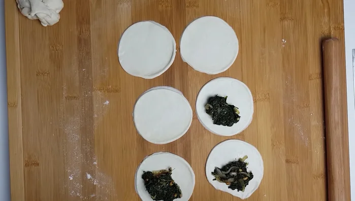Assemble sambousek: Place a heaped teaspoon of filling onto half of each dough circle. Fold the other half over and seal tightly, crimping the edges.