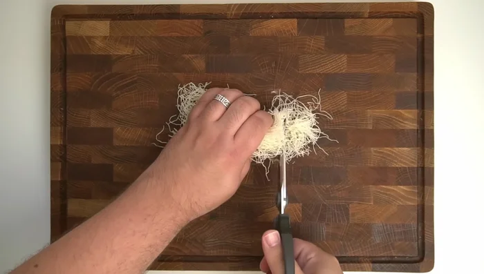 Cut 300g of kunafa pastry into 1cm segments using kitchen scissors.