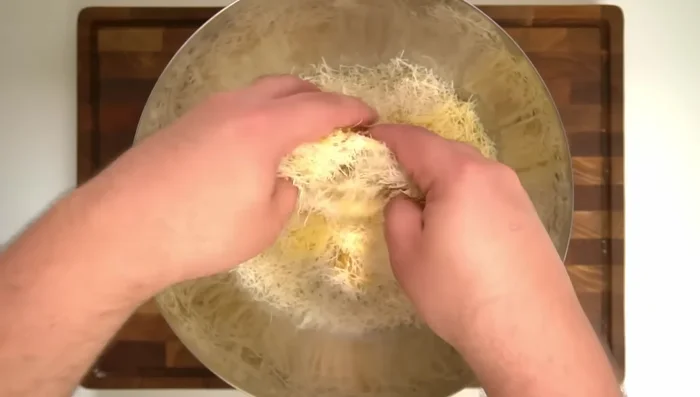 Toss the kunafa pastry with the melted clarified butter until evenly coated.