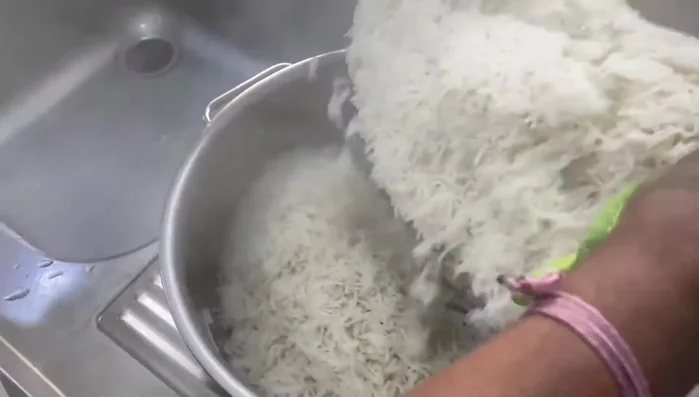 Cook the rice until it's thick enough that pressing a grain will break it into 2-4 pieces.
