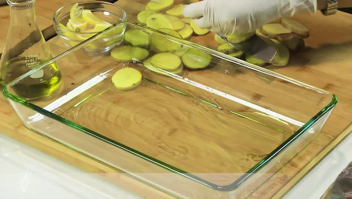 Drizzle olive oil in the bottom of the roasting pan, and arrange potato slices. Add lemon slices around the potatoes.