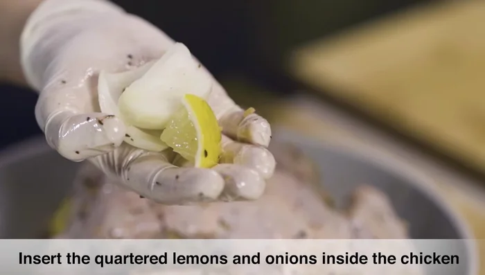 Fill the chicken cavity with quartered onions and lemons.