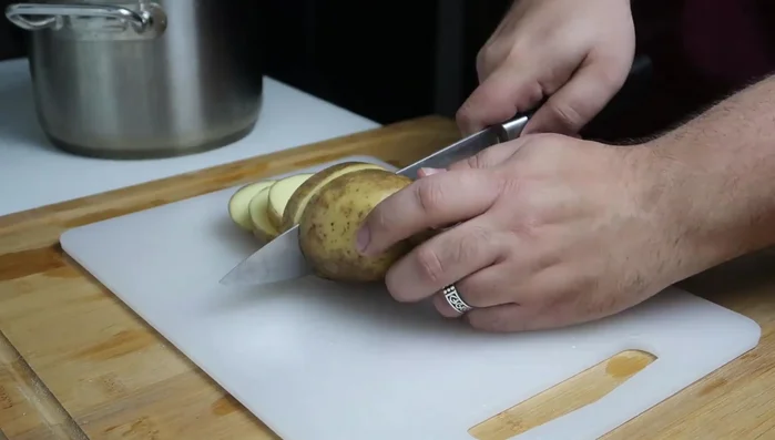Wash and peel a large potato; slice thickly. In a heavy-bottomed pot, layer the bottom with potato slices.