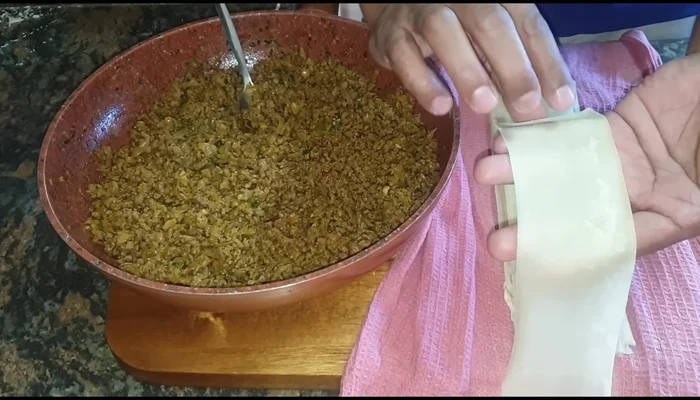 Assemble the samosas: Apply a flour and water paste to one edge of each strip. Place a spoonful of the filling at the center, fold, and seal the edges to form a cone shape.