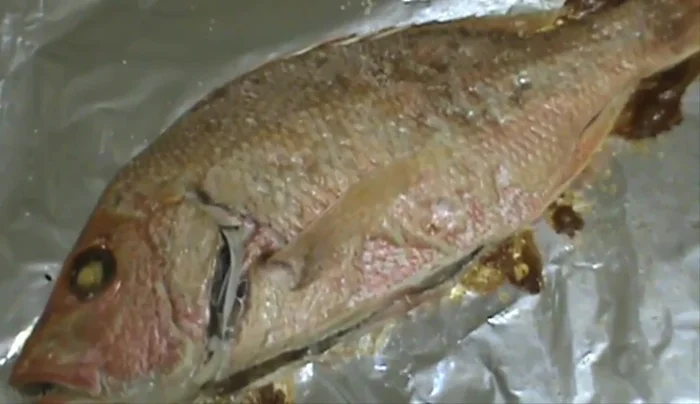 Remove the baked fish from the oven. Remove the skin carefully, leaving the scales on for easier peeling.