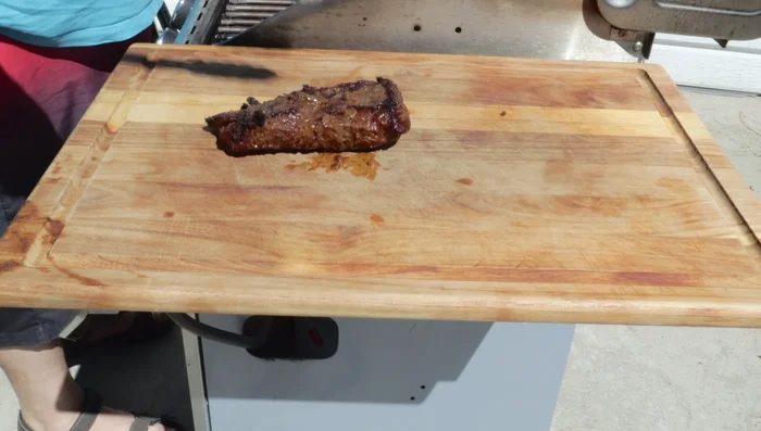Remove the steak from the grill and let it rest on a wooden cutting board.