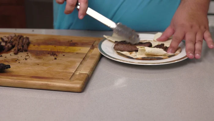 Assemble the shawarma: Open a pita bread, add the sliced beef, red onions, diced tomatoes, tahini, and Lebanese garlic sauce.