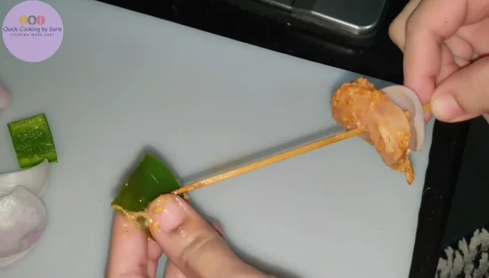 Prepare the skewers: Thread the marinated chicken onto skewers, alternating with onion and capsicum slices for presentation.