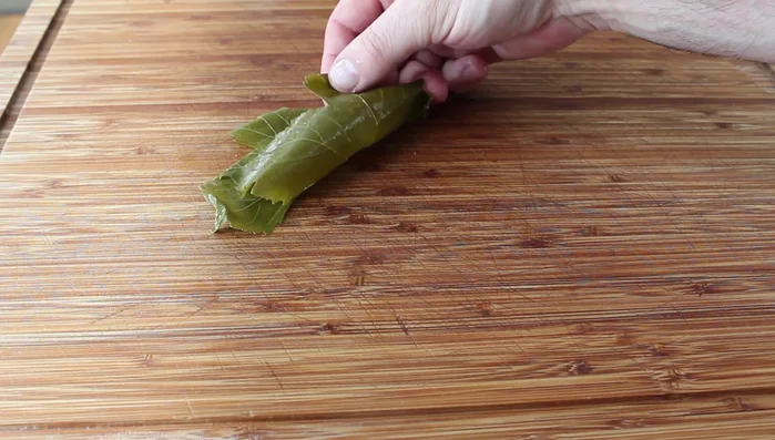 Stuff and roll the leaves: Place a grape leaf flat side down. Add a rounded tablespoon of stuffing to the center near the bottom. Fold the bottom of the leaf over the stuffing, then fold in the sides, and roll up tightly but not too firm. Repeat with remaining leaves.