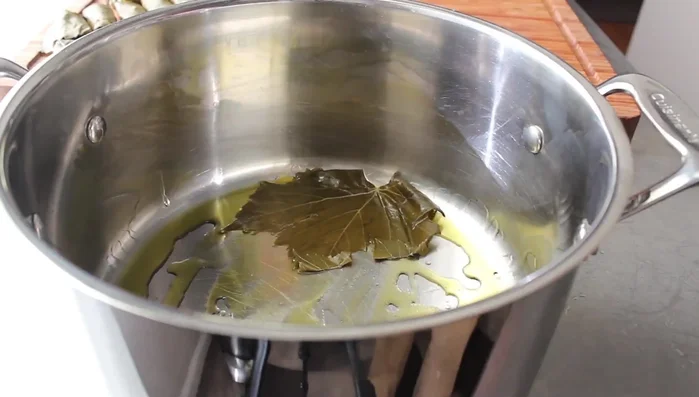 Layer the dolmas: Drizzle olive oil in the bottom of a pot. Layer the stuffed grape leaves in the pot, starting on the outside and working towards the center. Use extra grape leaves to fill any gaps and prevent the dolmas from unraveling. You can do multiple layers.