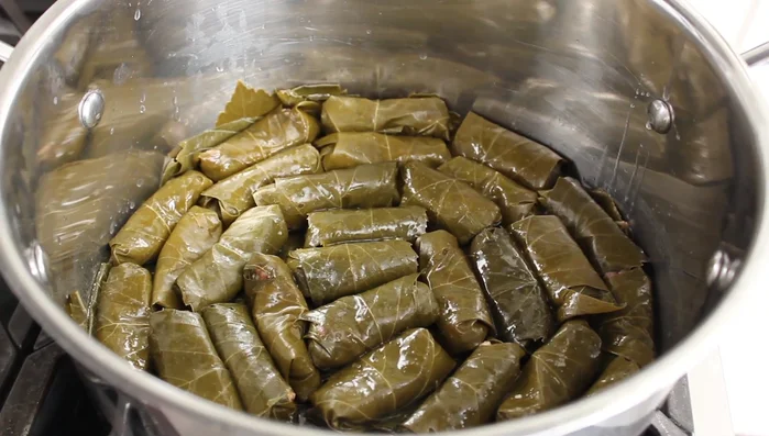 Cook the dolmas: Add fresh lemon juice and a drizzle of olive oil over the dolmas. Place a smaller plate in the center of the pot, and a larger plate on top to keep the dolmas submerged and prevent unraveling. Pour in chicken broth, ensuring no air pockets form. Bring to a simmer over medium-high heat, then reduce heat to low, cover, and cook for 45-60 minutes, or until the rice is tender. Remove plates halfway and check for doneness; add more cooking time if necessary.