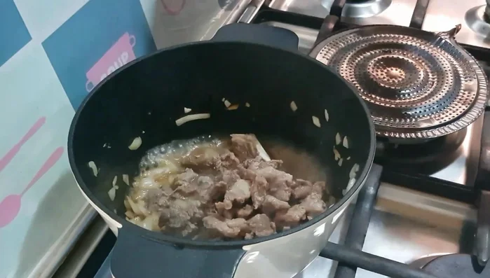 Add the cooked lamb/mutton and its juices to the pot. Add garlic powder/paste, chili flakes, and red bell pepper paste (or paprika powder). Mix well.