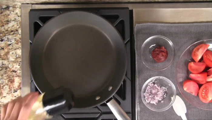 Heat a skillet over medium heat. Add vegetable oil, remaining chopped shallots, and tomato paste. Stir-fry for 15-20 seconds.