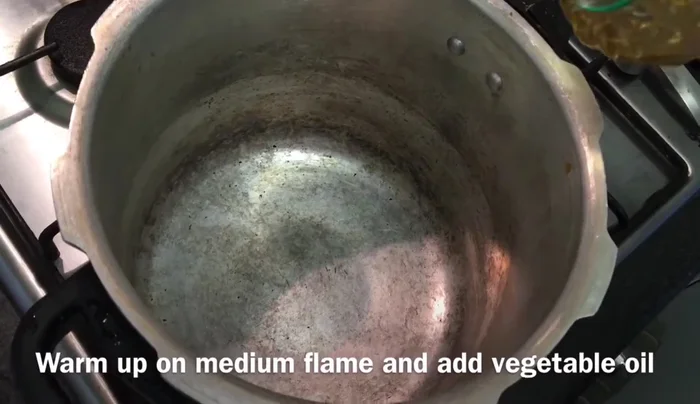 Heat a pressure cooker on medium flame and add vegetable oil. Add water and fry.