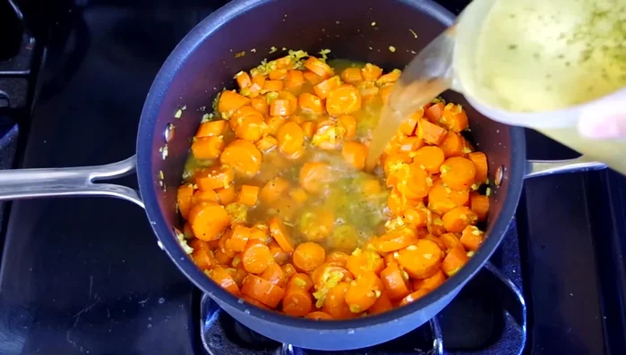 Add vegetable broth, water, and optional thyme. Bring to a simmer, then reduce heat to medium, partially cover, and cook for 25 minutes until carrots are tender.