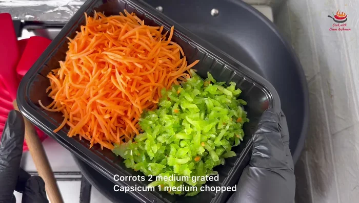 Heat olive oil in a pan. Add grated carrots and diced capsicum.