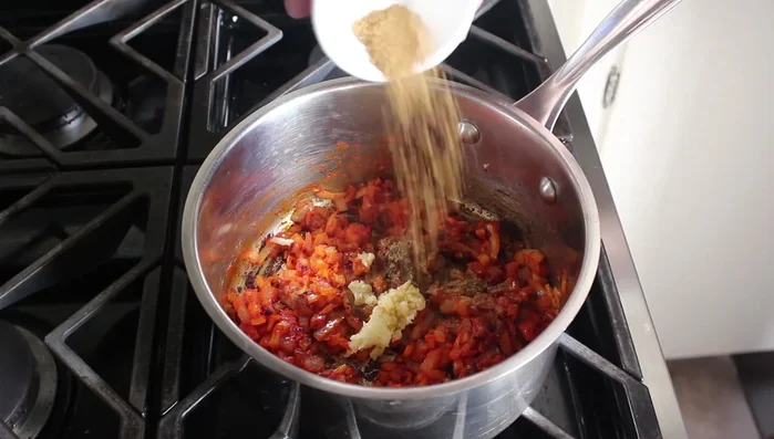 Add minced garlic, ground cumin, and a little cayenne pepper. Cook for 2 minutes.