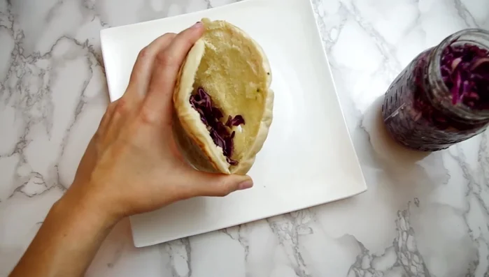 Prepare pickled cabbage by shredding cabbage and mixing with olive oil, apple cider vinegar, honey, salt, and pepper. Let it sit for a few minutes.