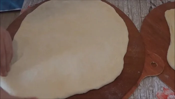 For the pizza: Stretch the pizza dough on parchment paper.