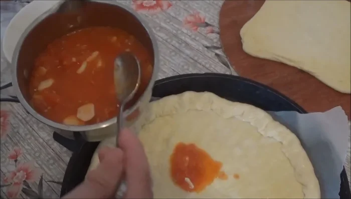 Spread tomato sauce over the pizza, then add more cheese.