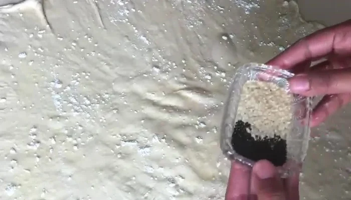 Sprinkle nigella seeds and white sesame seeds on the dough.