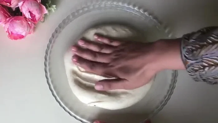Lightly grease a baking sheet, place the dough on it and gently stretch it out again. Brush the top with additional ghee and sprinkle with nigella and sesame seeds.
