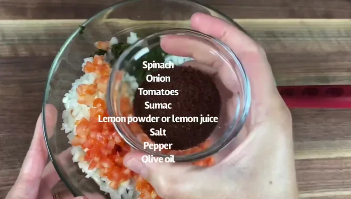 Combine spinach, onions, tomatoes, lemon powder (or juice), salt, pepper, olive oil, and pine nuts (optional). Mix well.