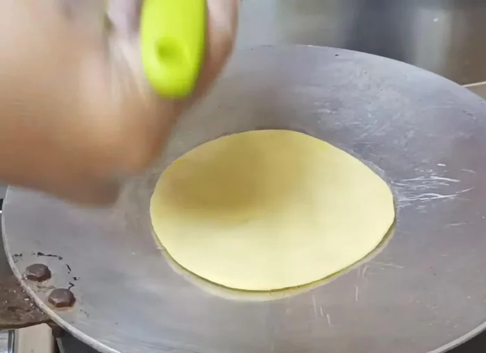 Place the rolled dough onto the hot tawa.