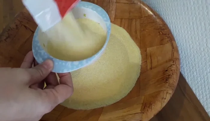 Mix medium semolina with sunflower oil. The speaker prefers not to use fine semolina as it makes the mbesses crispier on the outside and softer on the inside.