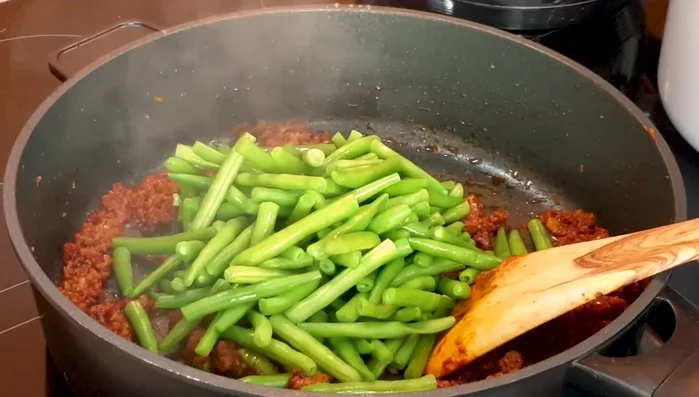 Add cooked beans to the meat mixture and stir.