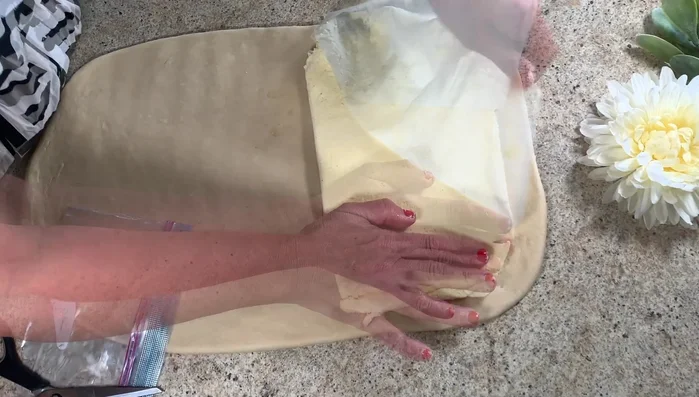 Roll the dough into a rectangle, add the chilled butter, and fold the dough. Roll again and chill for 1 hour. Repeat this process three times.