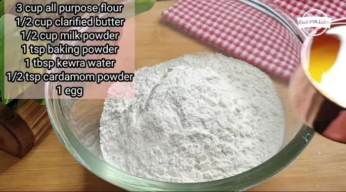 Combine dry ingredients: In a large bowl, mix 3 cups all-purpose flour, 0.5 cup desi ghee, 0.5 cup powdered sugar, 0.5 cup milk powder, 1 tbsp kewda water (or food essence), 0.5 tsp cardamom powder, and 1 tsp baking powder.