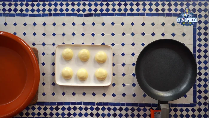 Flatten the dough balls: Spread oil on a large plate to prevent sticking. Take one dough ball, flatten it, coat with oil, flip, and flatten again until you can see the surface through the dough.