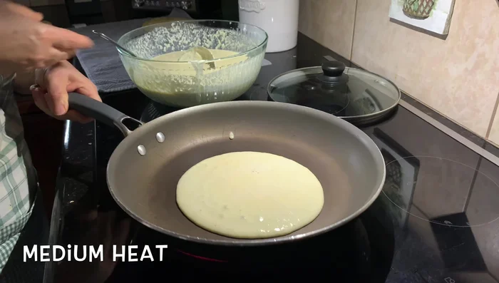 Pour a ladle of batter onto the hot pan, shaking the pan to spread evenly. Cook until bubbles appear on the surface and the white spots disappear.