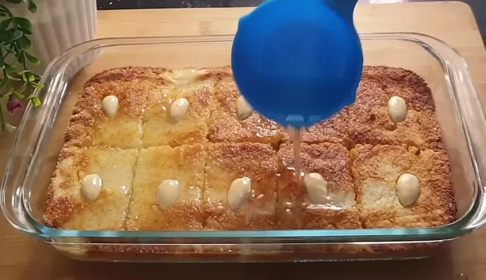 Pour half of the sugar syrup over the basbousa while it's still warm. Serve the remaining syrup on the side.