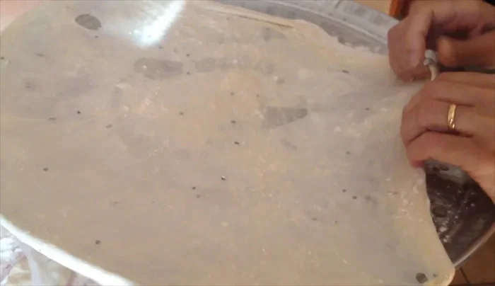 Carefully place the dough layers onto the prepared pizza pan, pulling and stretching them to create volume and air pockets.