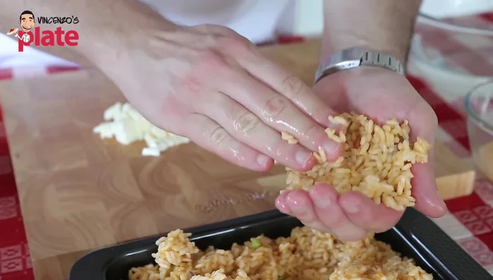 Take a portion of rice, flatten it, add a spoonful of meat sauce, some pork and veal, and a generous amount of mozzarella (250.64).