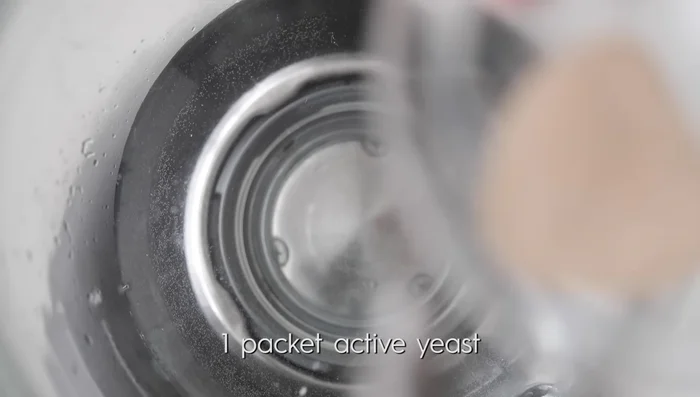 Activate yeast: In a stand mixer, combine hot water, active yeast, and half the sugar. Whisk by hand and let sit for 5-7 minutes until foamy. (40.379)