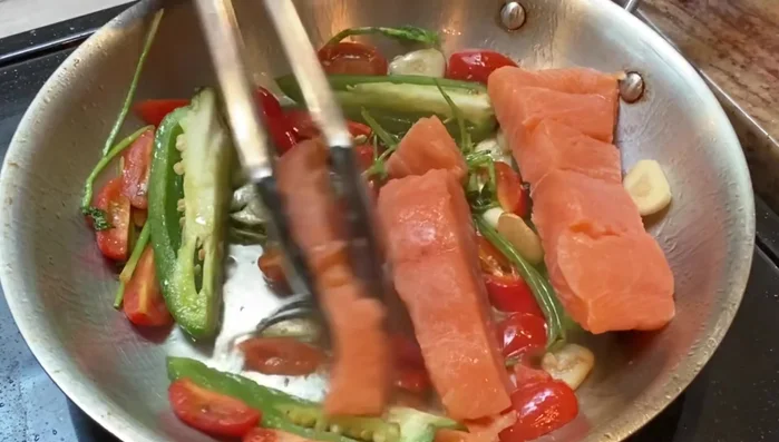 Place the fish on top of the vegetables. Season the fish with salt, black pepper, cooked fish seasoning mix (or paprika, garlic powder, onion powder, chili flakes), and chicken seasoning/Kansome seasoning.