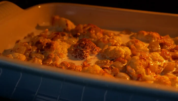 Bake at 180°C (356°F) for 30-40 minutes until browned and bubbling. Let cool slightly before garnishing with chopped parsley, fried pine nuts, and chili flakes.